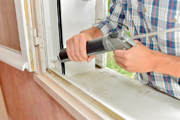 image of a homeowner sealing window to prevent cooled air from escaping