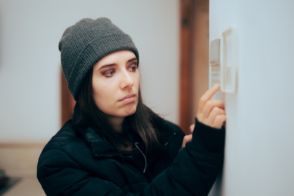 image of homeowner adjusting thermostat depicting running out of propane in winter