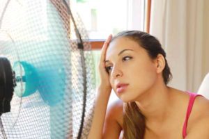 image of a homeowner keeping cool with fan due to broken air conditioner