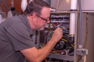 image of an hvac tech fixing a gas furnace