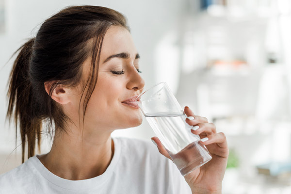 image of homeowner drinking water to avoid heat exhaustion when air conditioner is broken