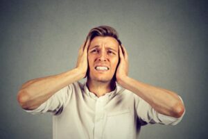 image of homeowner covering ears due to air conditioner making noise