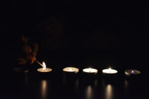 Homeowner lighting up a row of candles in the dark with a match due to blackout