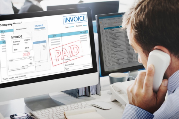 business owner on the phone settling payment for invoice in the computer