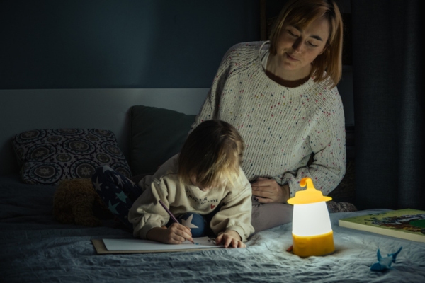 mom and kid studying in the dark with portable lamp due to blackout