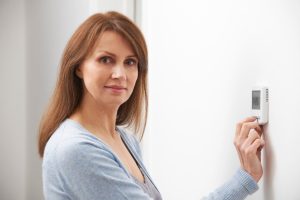 woman adjusting thermostat