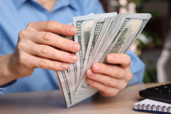 image of a homeowner's hand holding and counting money depicting cost considerations for ducted or ductless cooling systems