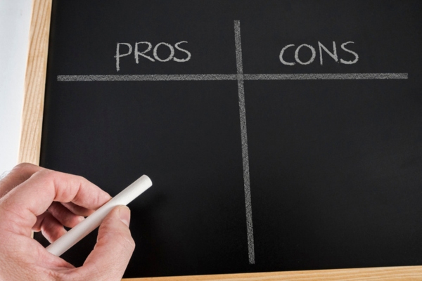 pros and cons written on a board with hand holding a chalk depicting ducted vs ductless air conditioning systems